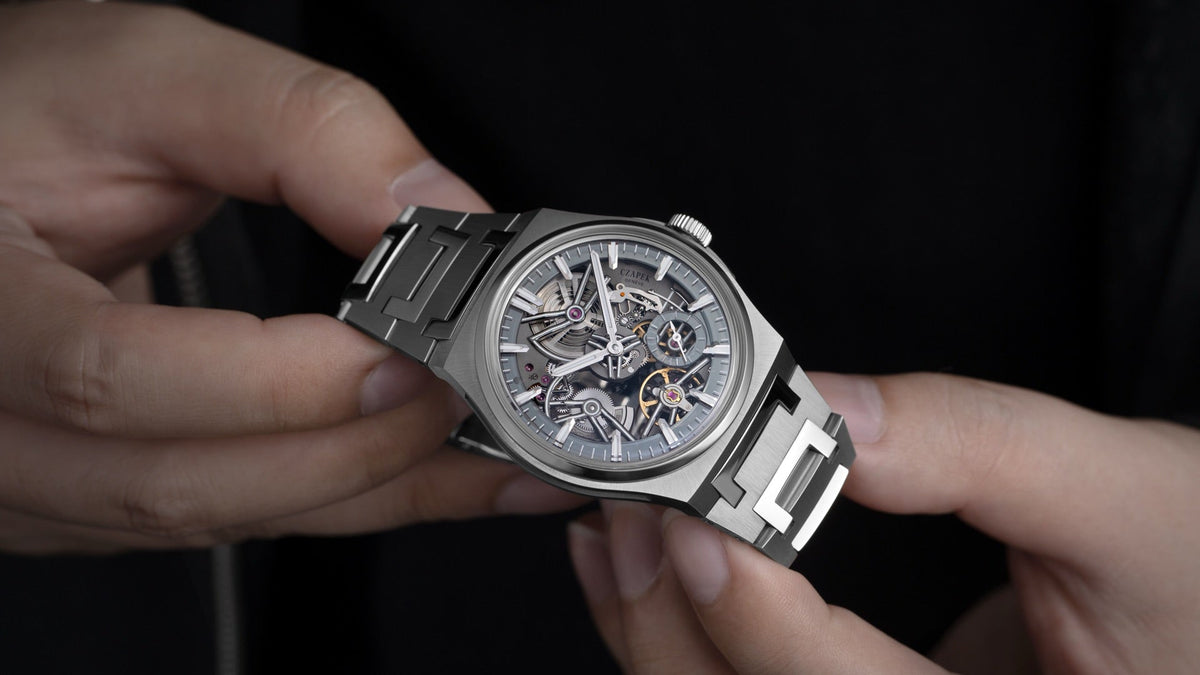 Czapek Antarctique Révélation Spectrum held in two hands, close view of the skeletonised dial and steel bracelet