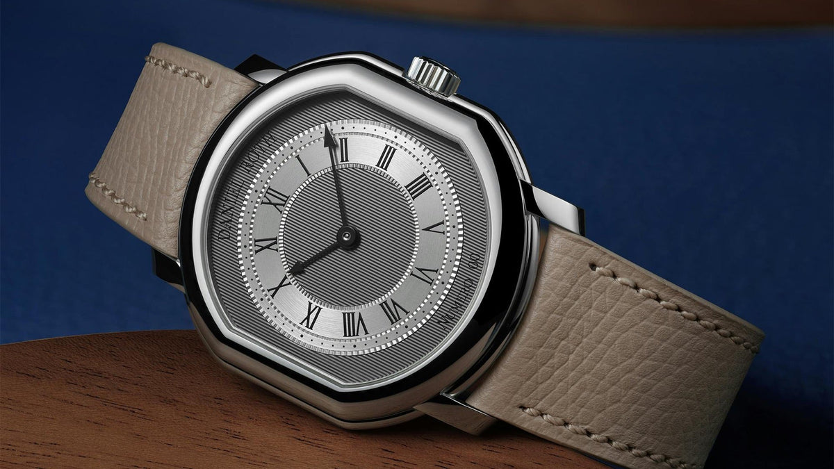 DANIEL ROTH Extra Plat Platinum resting on wood, with a blue backdrop and coiled leather strap