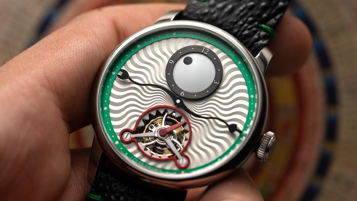 Louis Erard Time Eater Tourbillon Green held in hand over a colourful patterned rug