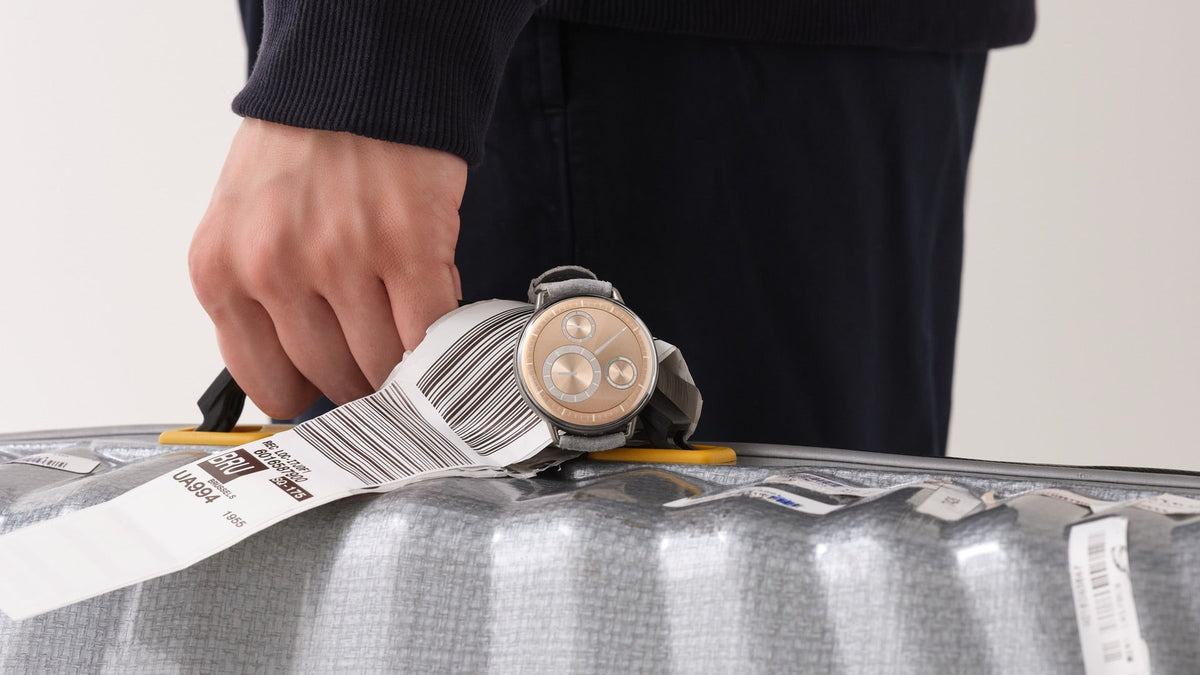 Ressence TYPE 1 Round Rose Gold worn on the wrist, resting on a suitcase with an airport luggage tag