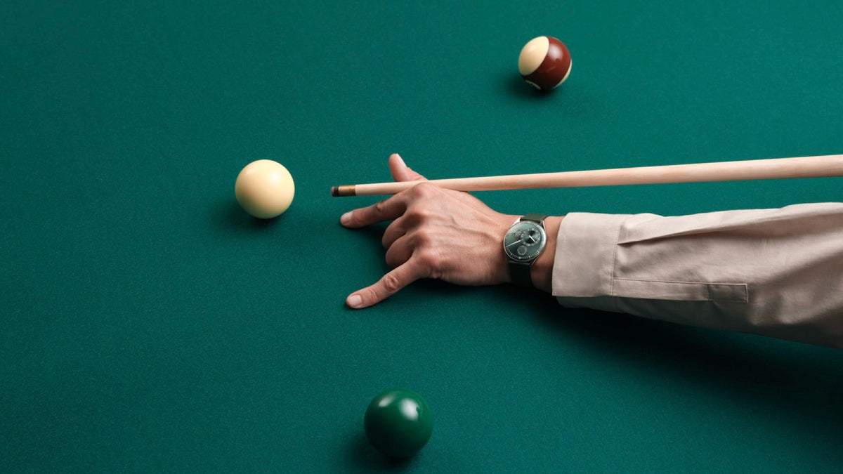 Ressence TYPE 11 Pine worn on the wrist, cueing a shot on a green billiard table