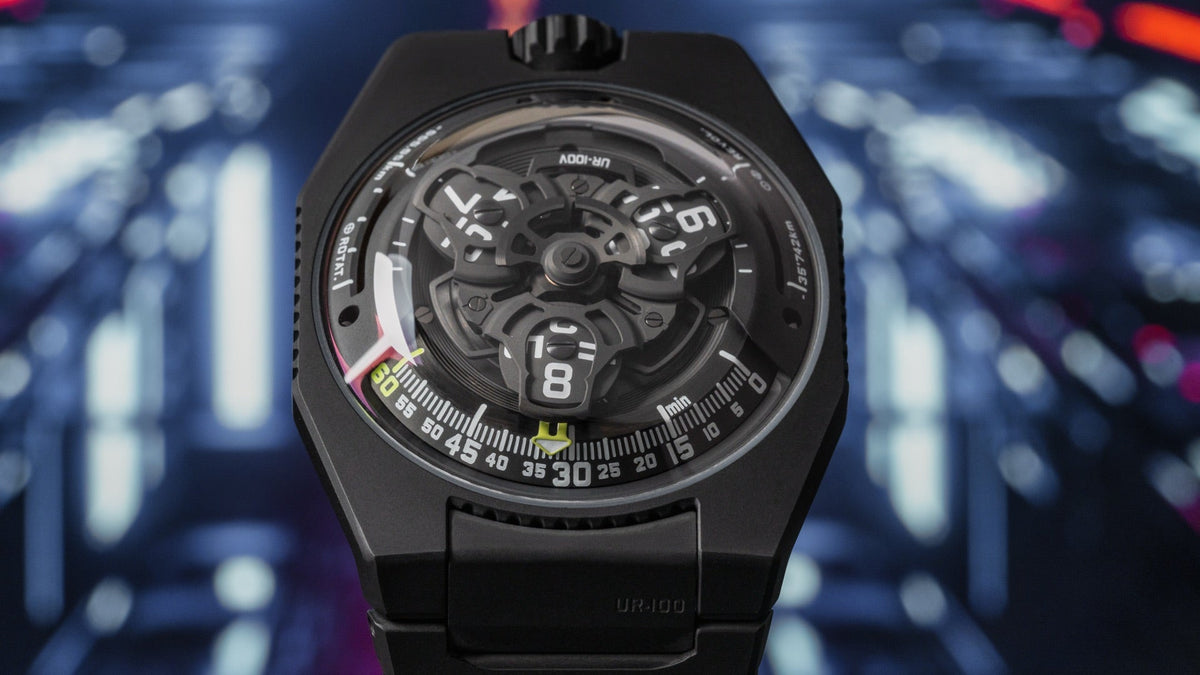 URWERK UR-100V Full Black Titanium Jacket against blurred city lights, black titanium case and bracelet